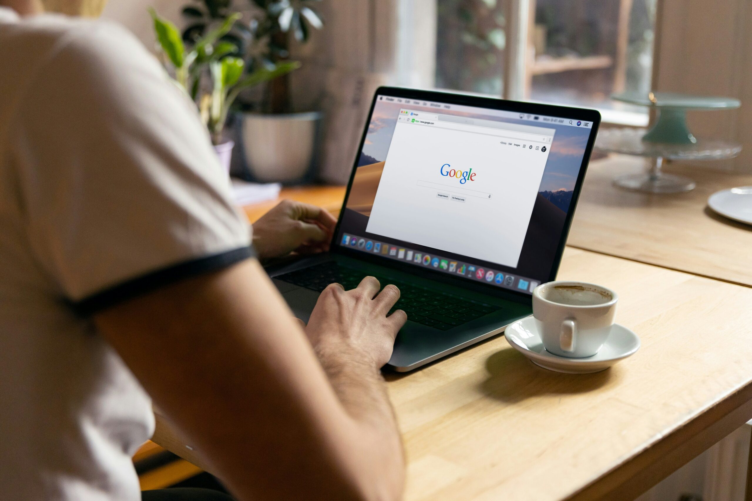 A person sitting on a chair, focused on their MacBook screen displaying Google's organic search results.
