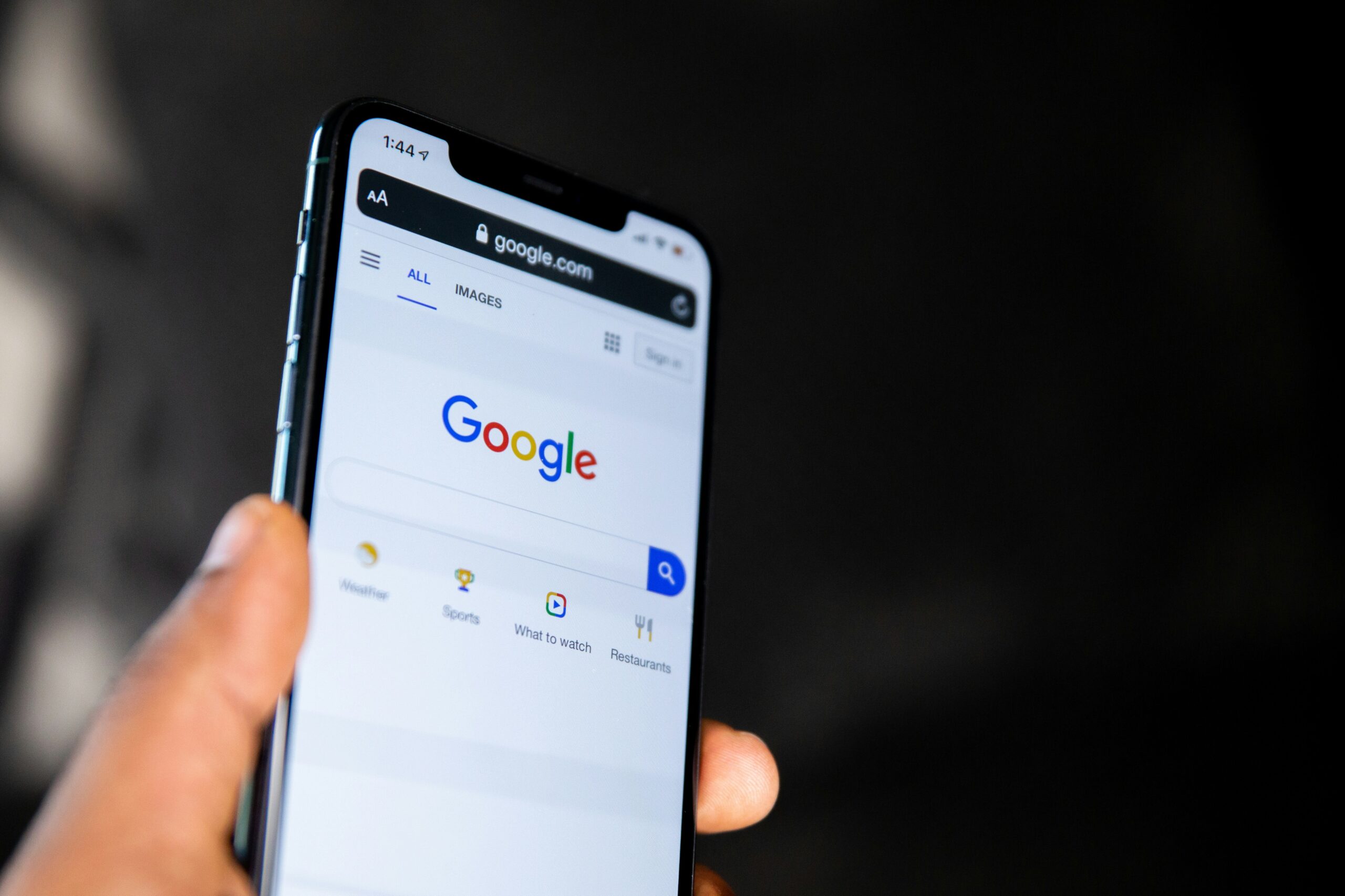 iPhone screen showing a Google Ads or Search, held by someone in Johor Bahru, representing online information seeking.