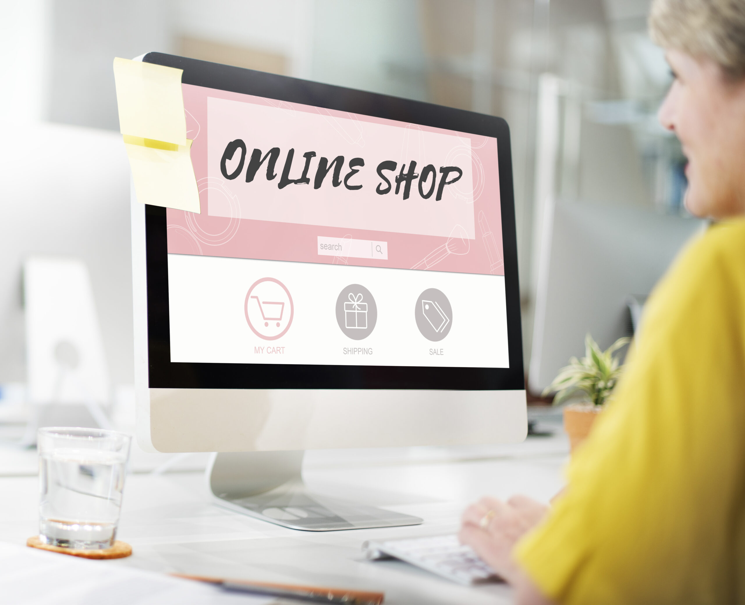 Computer screen showing an e-commerce website with products, being browsed by a woman, representing online shopping.