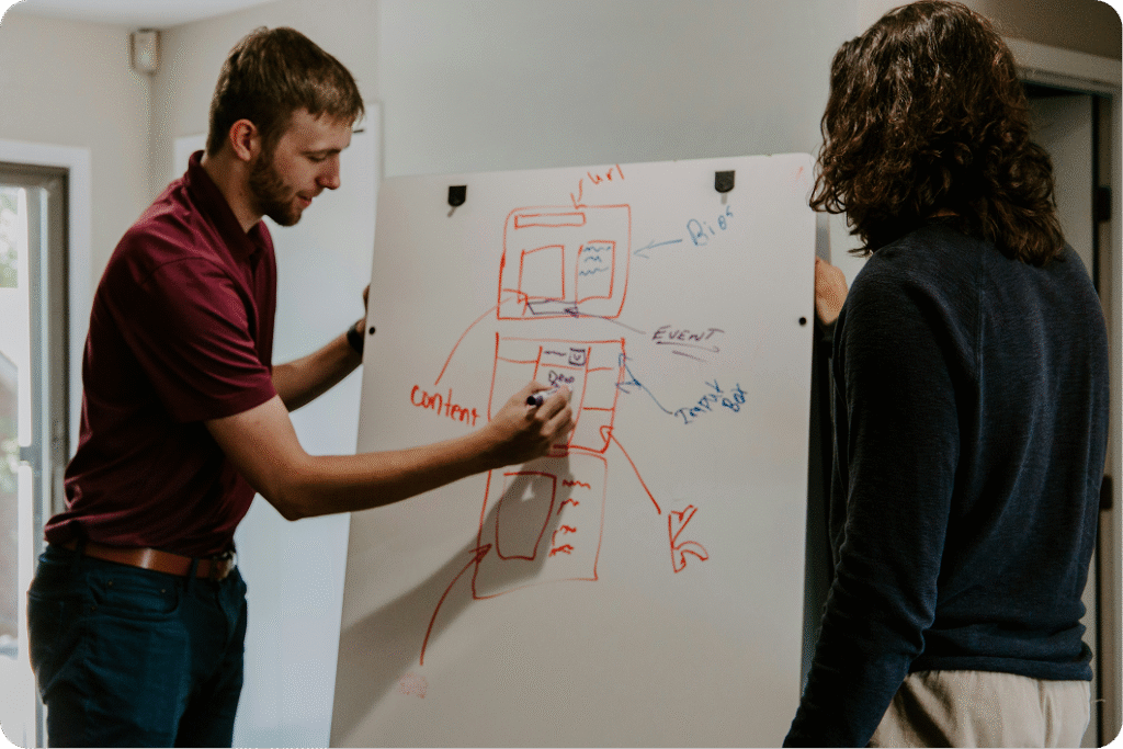 Two colleagues, male and female, collaborating over website wireframe designs on a digital screen or whiteboard.